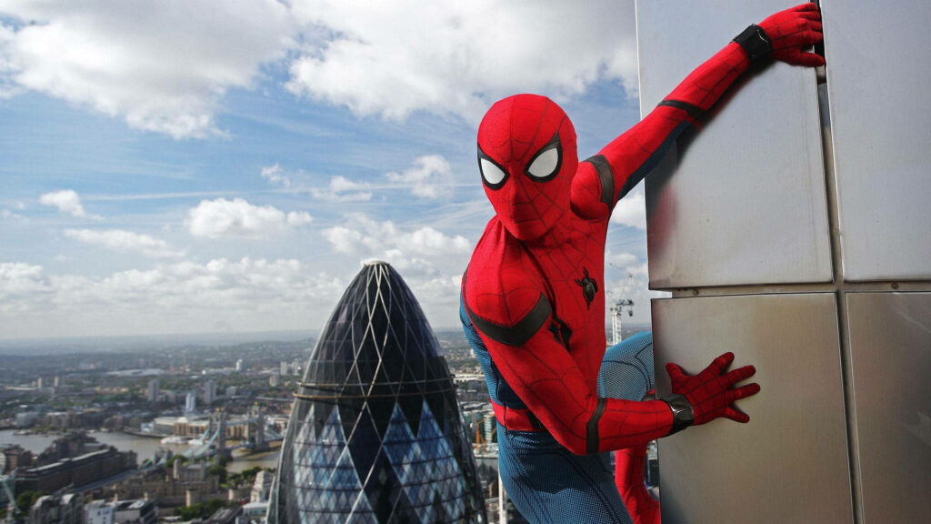 Spider-Man climbs a metallic skyscraper overlooking London skyline with Gherkin and Tower Bridge Wallpaper