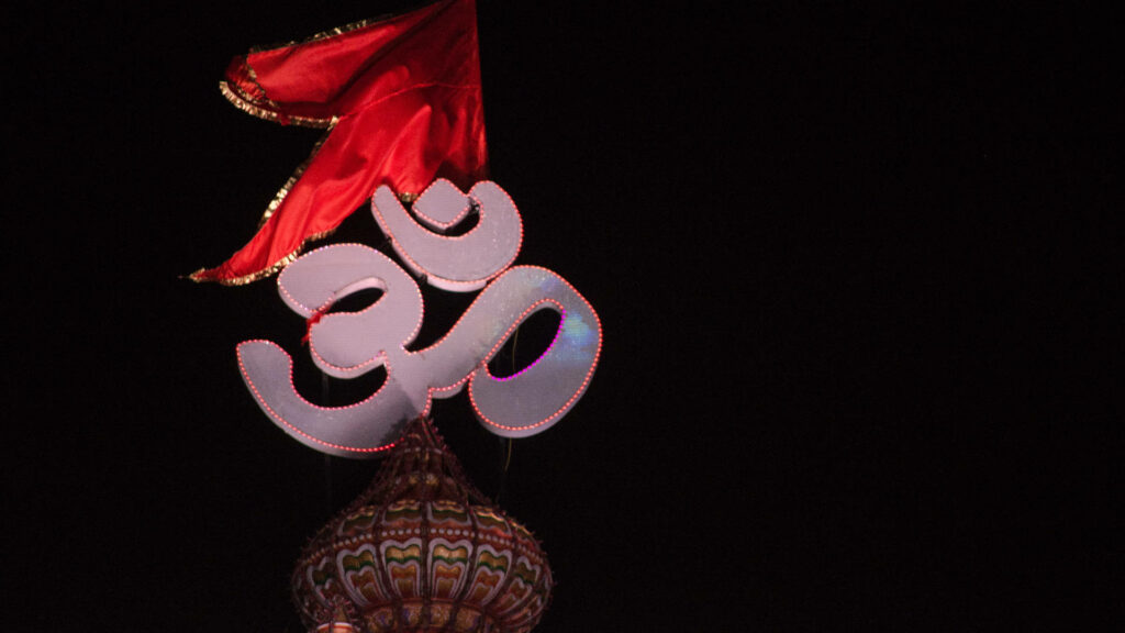 Om Overlooking: A Red Flagged Tribute on Building Background Wallpaper