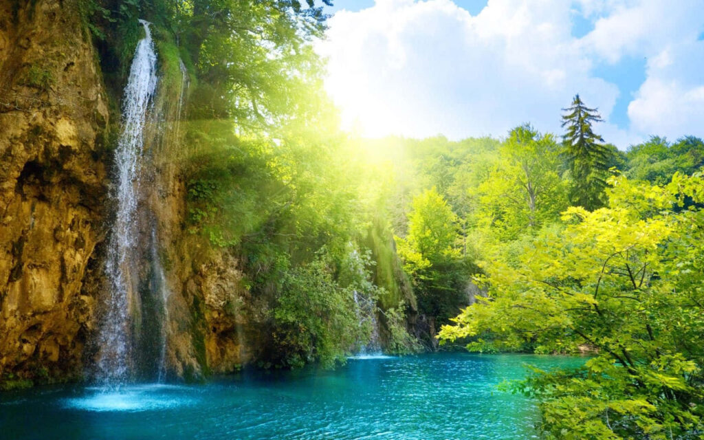 Tranquil Oasis: A Captivating Wallpaper of a Blissful Sunny Waterfall Paradise