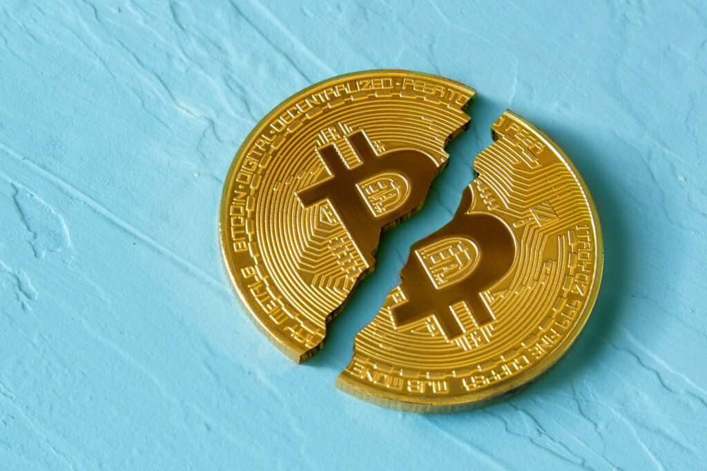 Split golden Bitcoin coin on textured blue surface symbolizing digital currency loss wallpaper