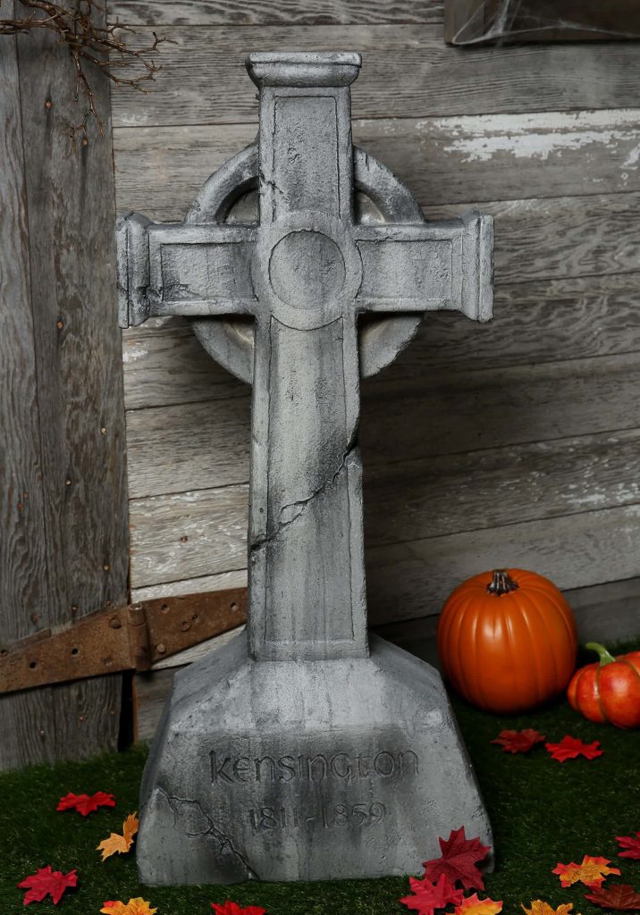 Halloween wallpaper with weathered gray Celtic cross gravestone and autumn decorations