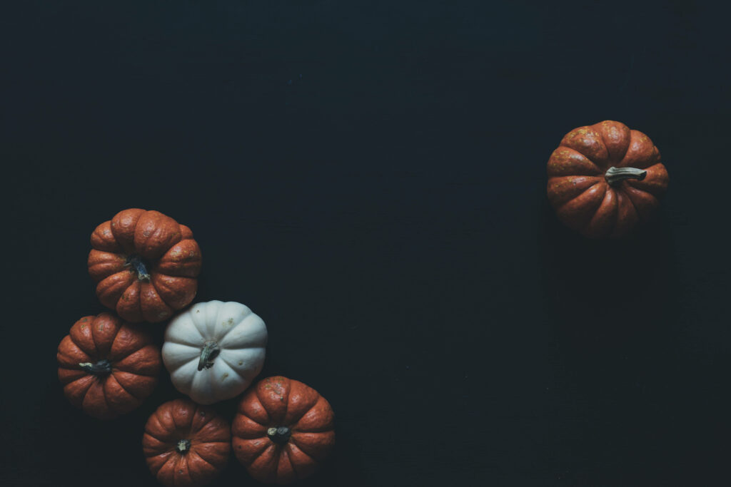 Minimalist black wallpaper with chic orange and white pumpkins for stylish Halloween decor