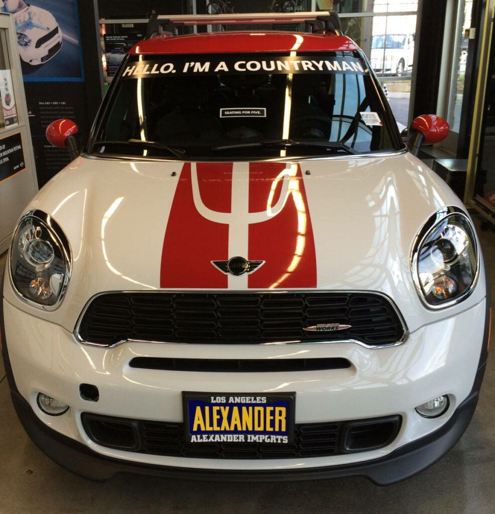 White Mini Countryman with red racing stripes in modern showroom with Hello I'm a Countryman text Wallpaper