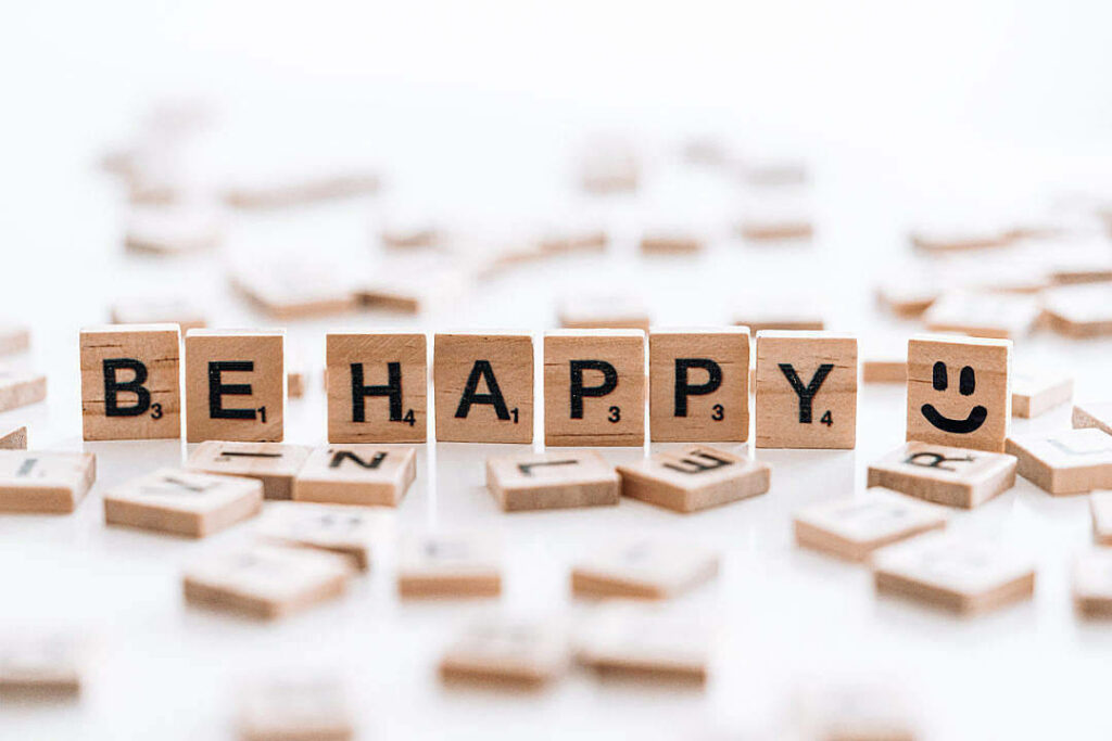 Radiate Positivity: Inspiring Wallpaper featuring Scrabble Tiles Spelling Out a Message to Embrace Happiness in Life
