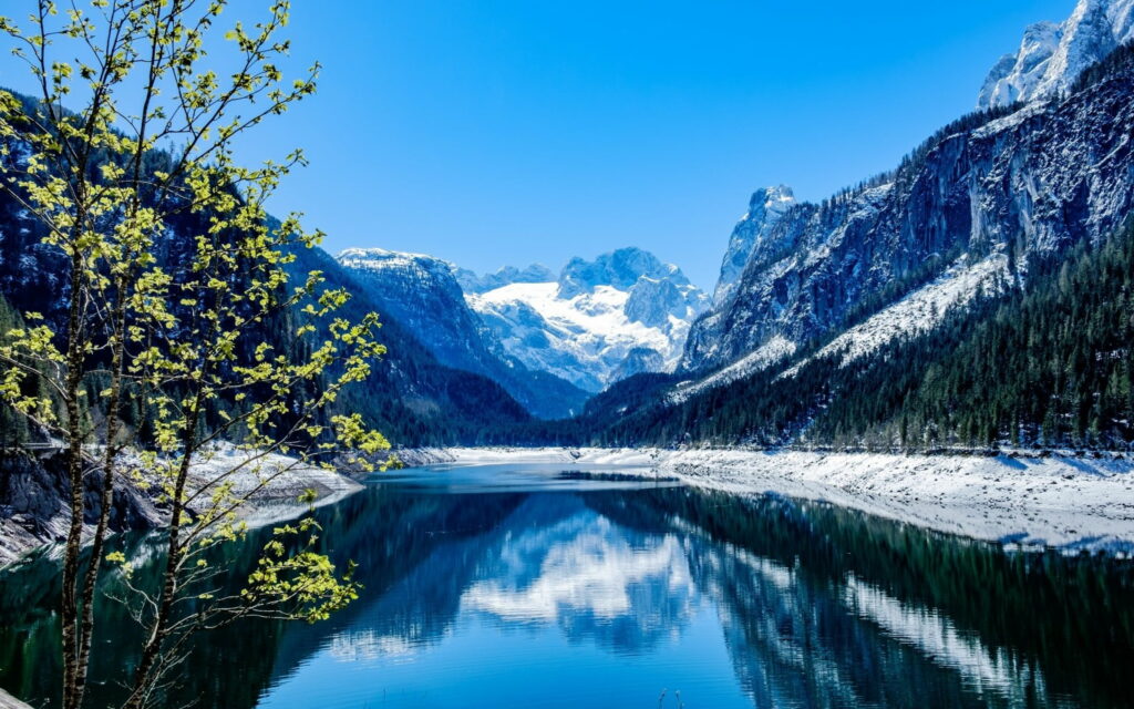 Spring Bliss: Majestic Snow-Capped Peaks Reflecting on a Peaceful Mountain Lake Wallpaper