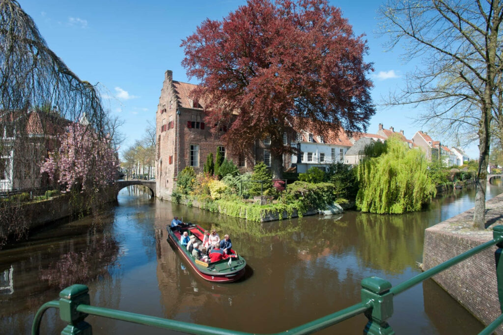 Springtime Amersfoort canal boat tour with historic buildings blooming trees and blue sky Wallpaper