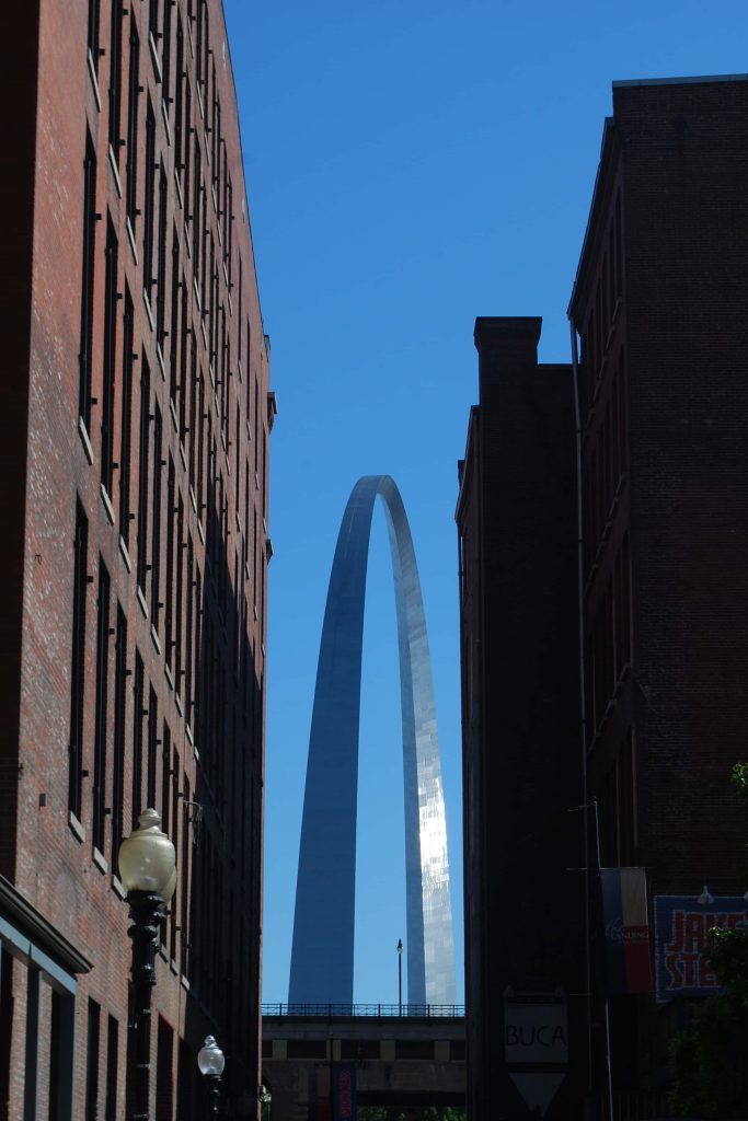 Gateway Arch in St Louis framed by historic brick buildings under a clear blue sky urban landmark Wallpaper