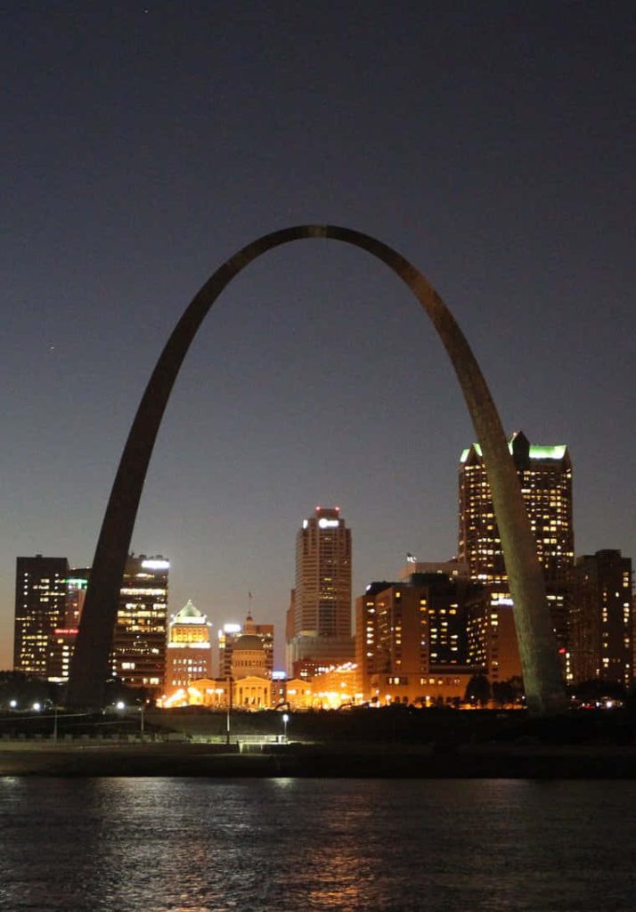 St Louis Gateway Arch at night with glowing downtown skyline reflecting on dark river wallpaper