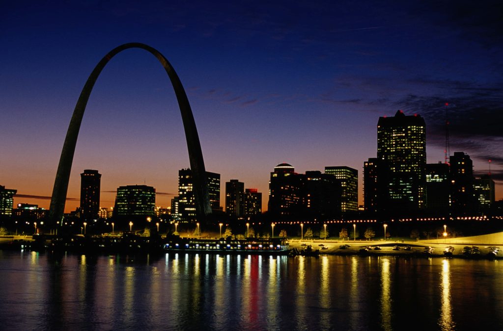 St Louis skyline at night with glowing Gateway Arch and city lights reflecting on Mississippi River Wallpaper