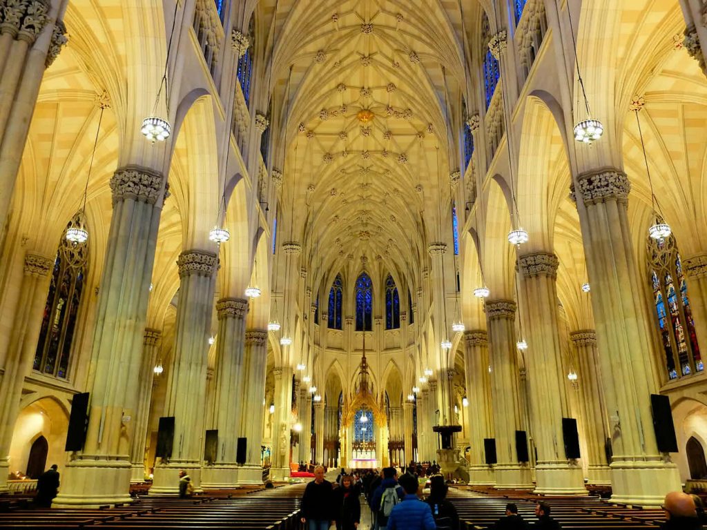 Inside St Patricks Cathedral NYC vaulted ceiling columns blue stained glass elegant pendant lights Wallpaper
