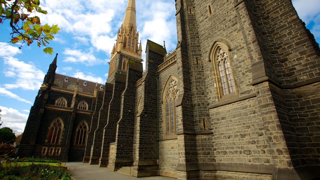 St Patricks Cathedral Melbourne Gothic architecture dark stone walls soaring spire blue sky Wallpaper