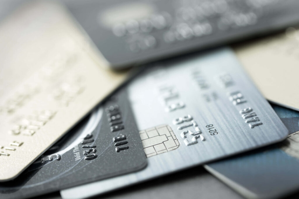 Close up of stacked silver and black credit cards showing embossed numbers and metallic chips Wallpaper