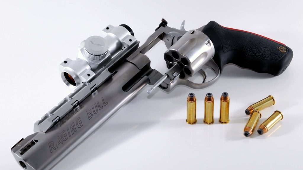 Stainless steel Taurus Raging Bull 44 Magnum revolver with mounted optic and cartridges on white background Wallpaper