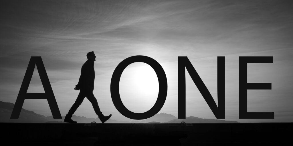 Silhouette walking past bold alone text with mountain horizon under moody black and white sky Wallpaper