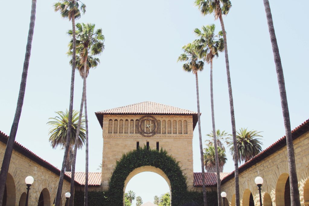 Stanford University Main Quad with palm trees ivy arch clock tower bright sky 4K wallpaper