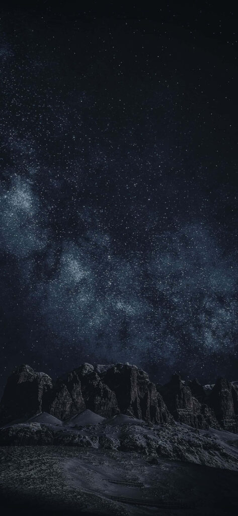 Stunning night sky wallpaper featuring the Milky Way over dark mountain peaks.