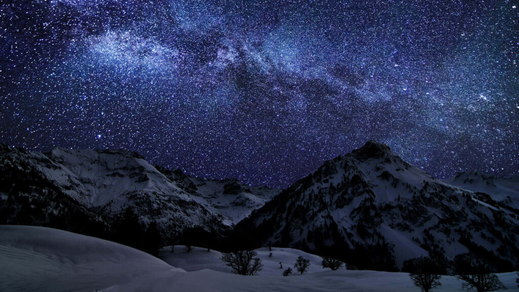 Starry night sky over snow-covered mountains with a stunning Milky Way, serene nature wallpaper.