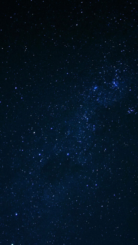 Mesmerizing starry night wallpaper with deep blue sky and shimmering stars for mobile display