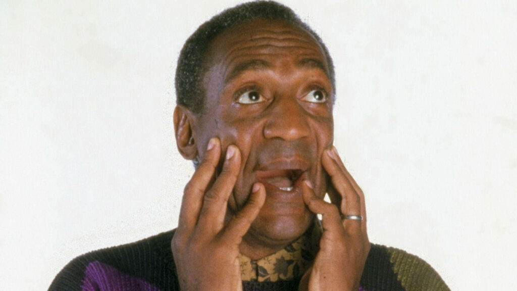 Bill Cosby startled scared expression hands on face plain wallpaper background