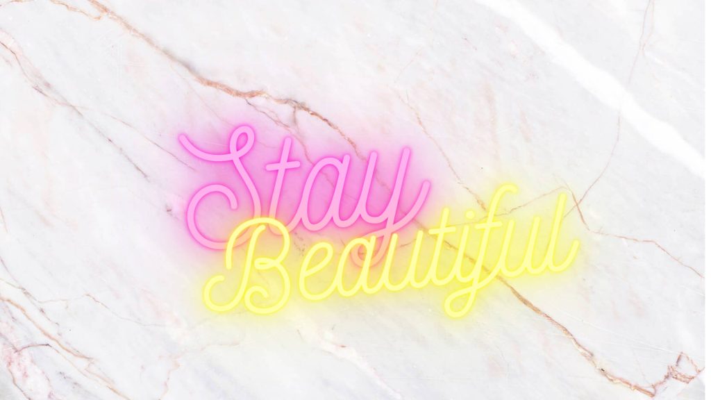 Chic wallpaper with neon Stay Beautiful script glowing in pink and yellow on white marble background