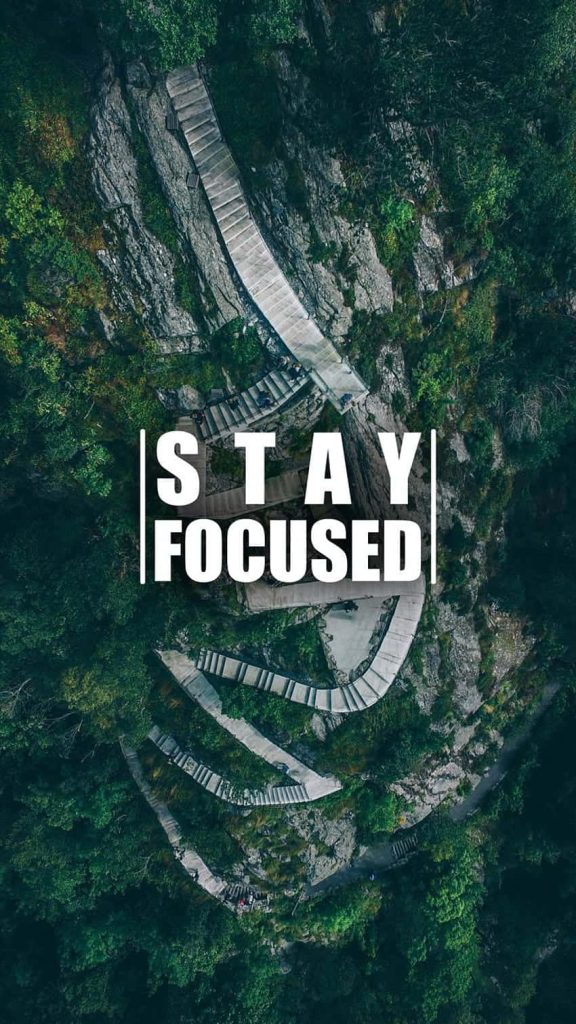 Aerial view of stone staircase winding through forested mountains with Stay Focused text wallpaper