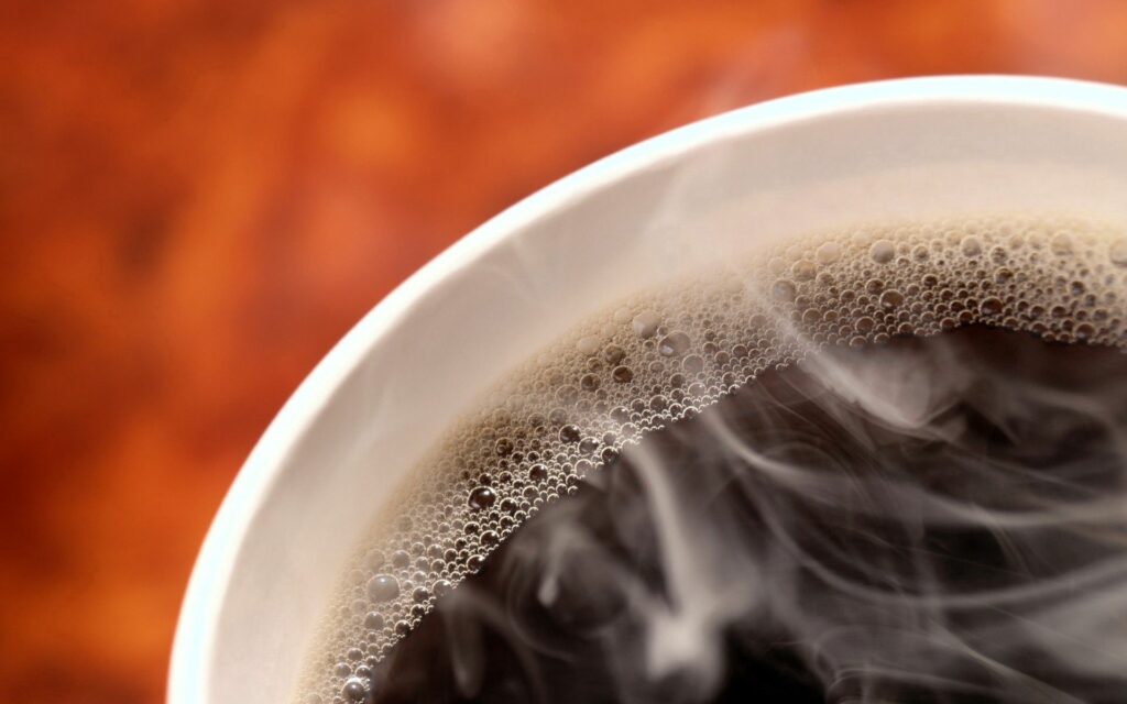 Steaming Black Coffee Close-Up with Frothy Bubbles - Warm Wallpaper