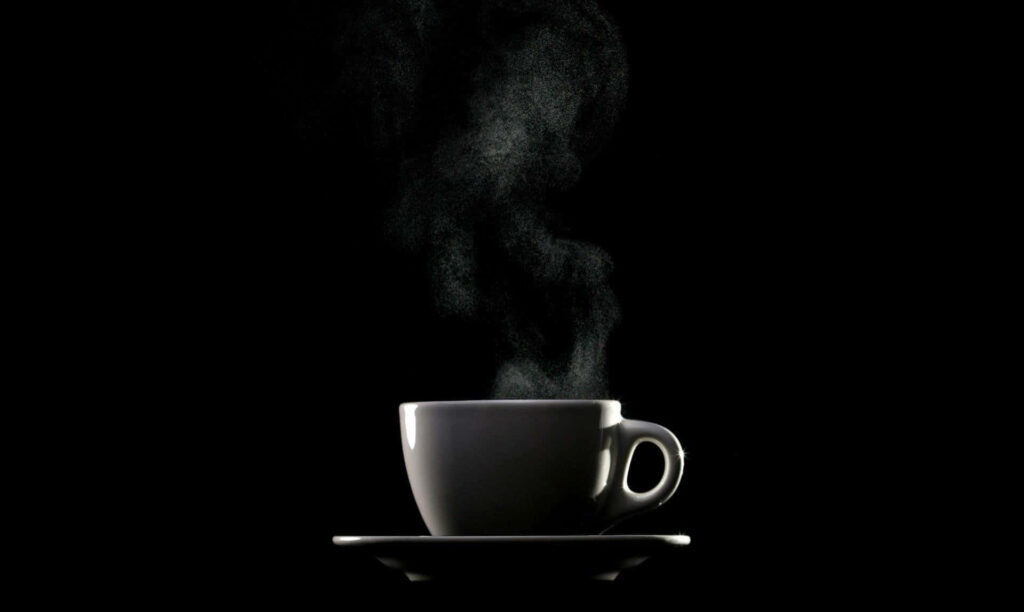 Steaming cup of black coffee on saucer dark background inviting refreshing morning start wallpaper