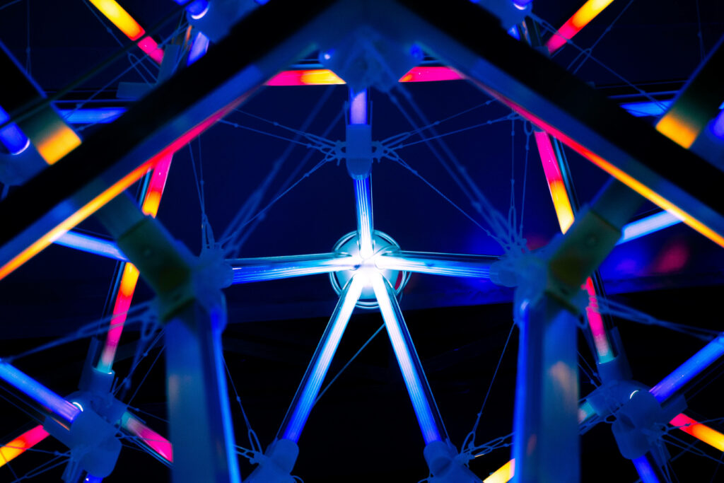 Futuristic geometric steel framework with vibrant neon blue orange magenta lights background Wallpaper