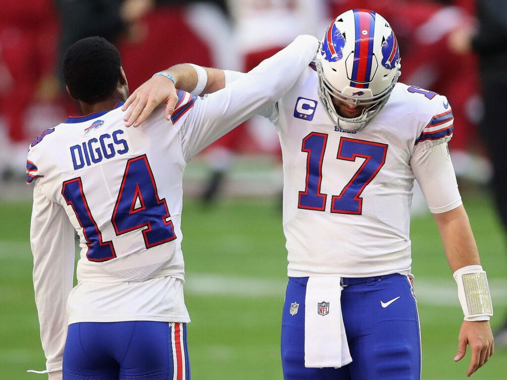 Stefon Diggs and Josh Allen in white Buffalo Bills uniforms share teamwork moment on NFL field Wallpaper