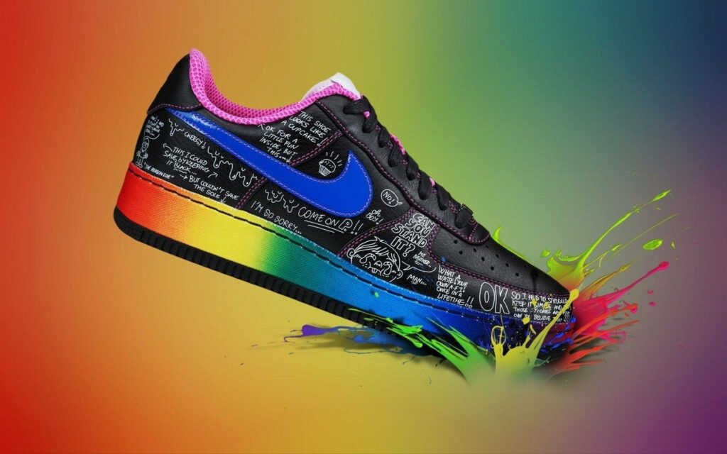 Vibrant Nike graffiti-style sneaker with colorful accents on dynamic rainbow splash background Wallpaper