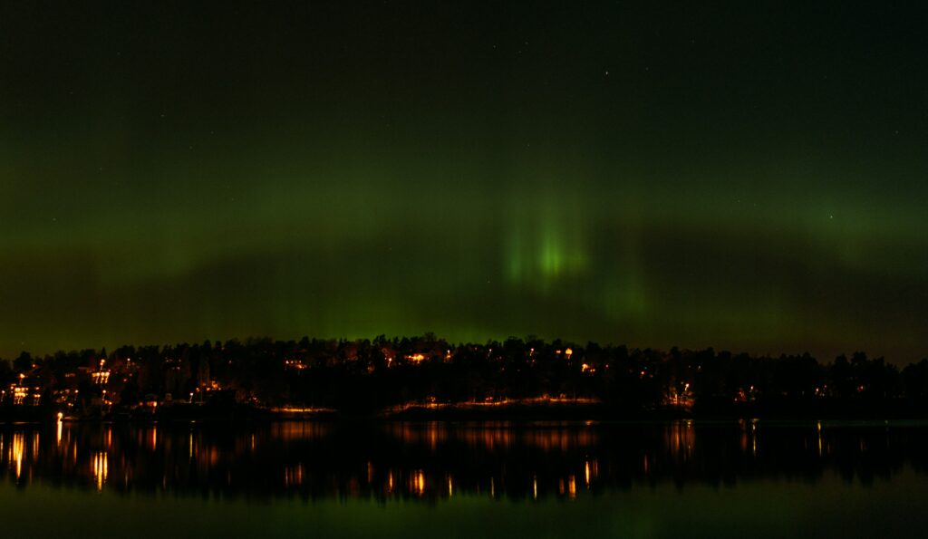 Stockholm night cityscape with northern lights reflecting on calm water serene urban wallpaper