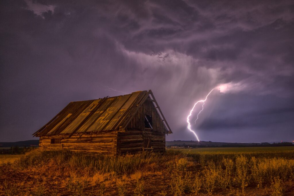 Old wooden barn under stormy sky with vivid lightning and swirling dark clouds rural scene Wallpaper