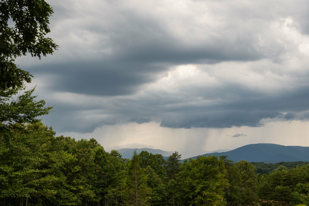 Dramatic stormy sky over lush green forest and distant mountains vibrant nature wallpaper background