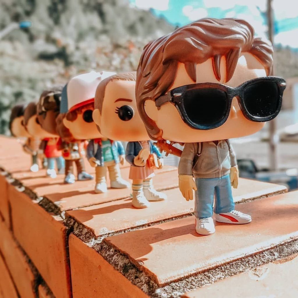 Stranger Things Funko Pop Steve Eleven Dustin vinyl figures on brick ledge in natural light Wallpaper