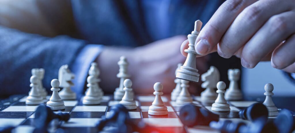 Close-up of a suited player moving white king in intense chess game with blue ambiance background Wallpaper