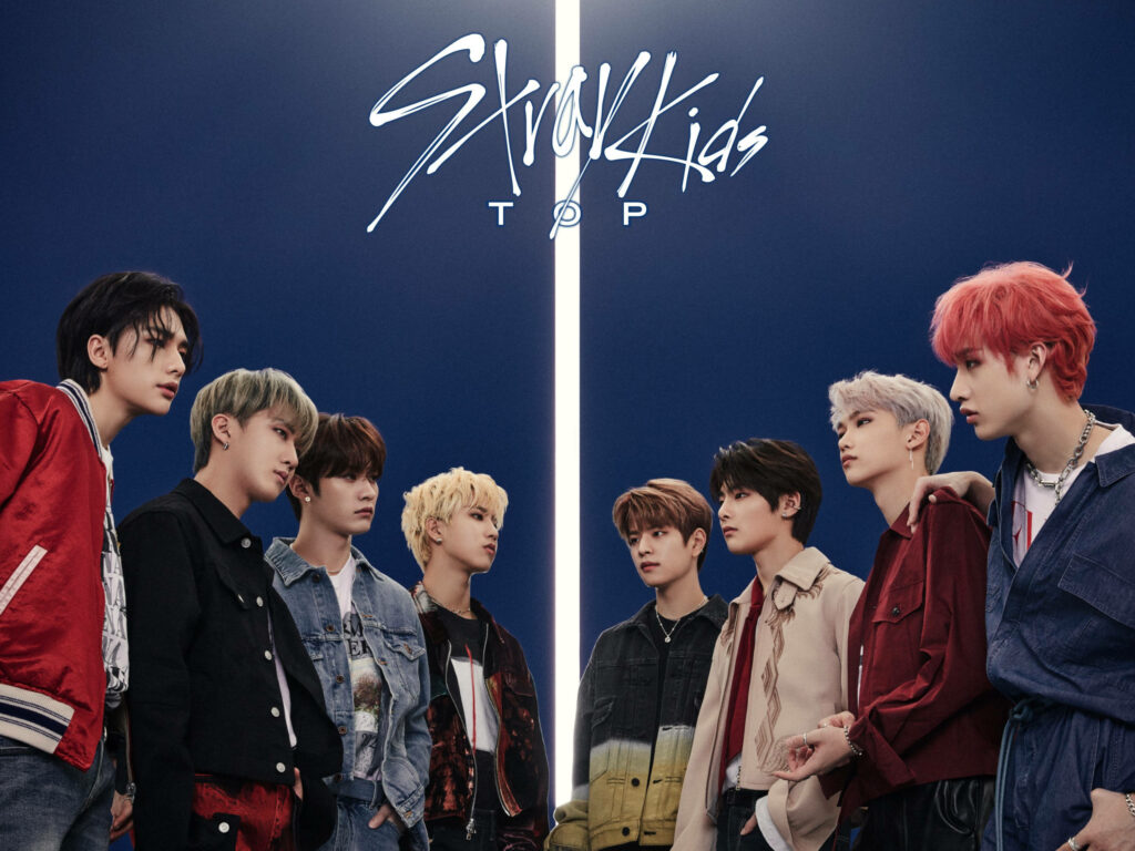 Stray Kids Top wallpaper with eight members facing each other under glowing vertical light background