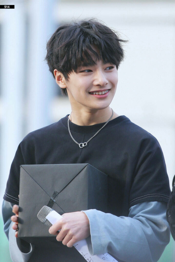 Stray Kids youngest member smiling brightly holding a gift vibrant Kpop wallpaper background