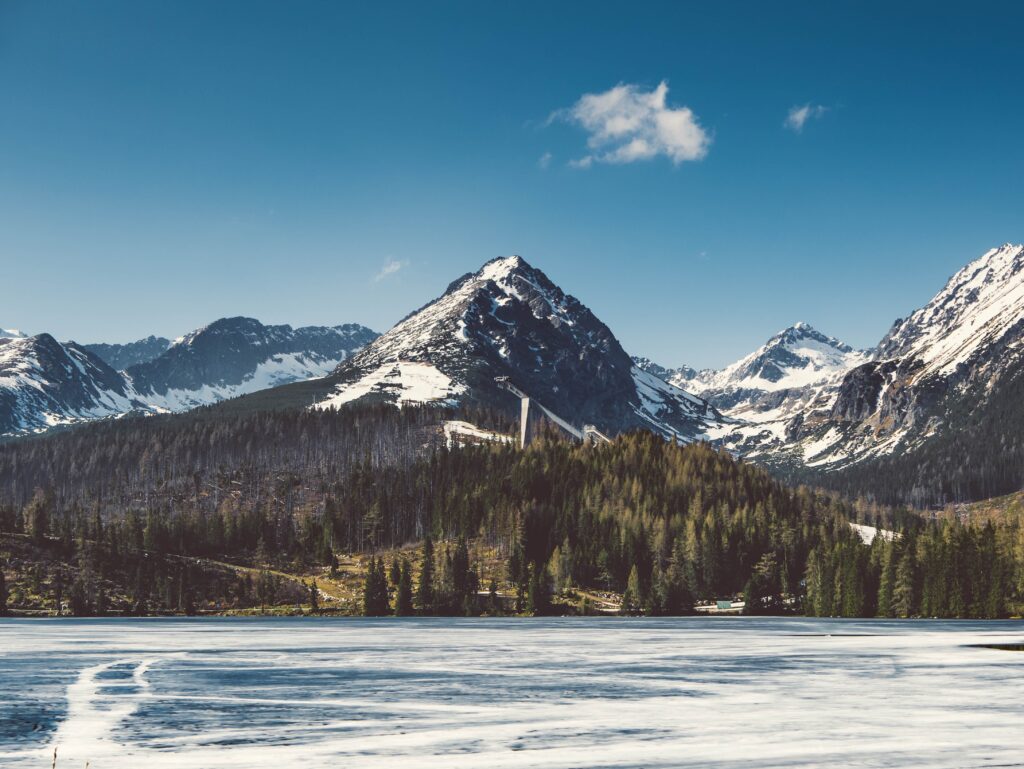 Strba Tarn Slovakia alpine lake reflecting snow-capped mountains and dense evergreen forests Wallpaper