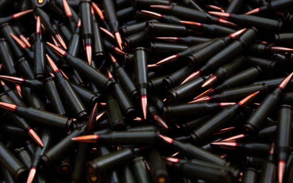 Close-up of 7.62x39mm bullets with green steel casings and copper tips in dense pile background Wallpaper