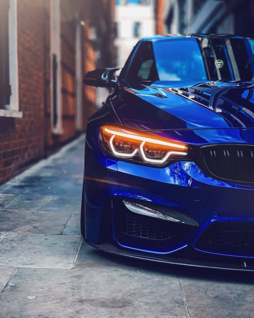 Blue BMW parked on city street with sleek front and glowing headlights modern wallpaper