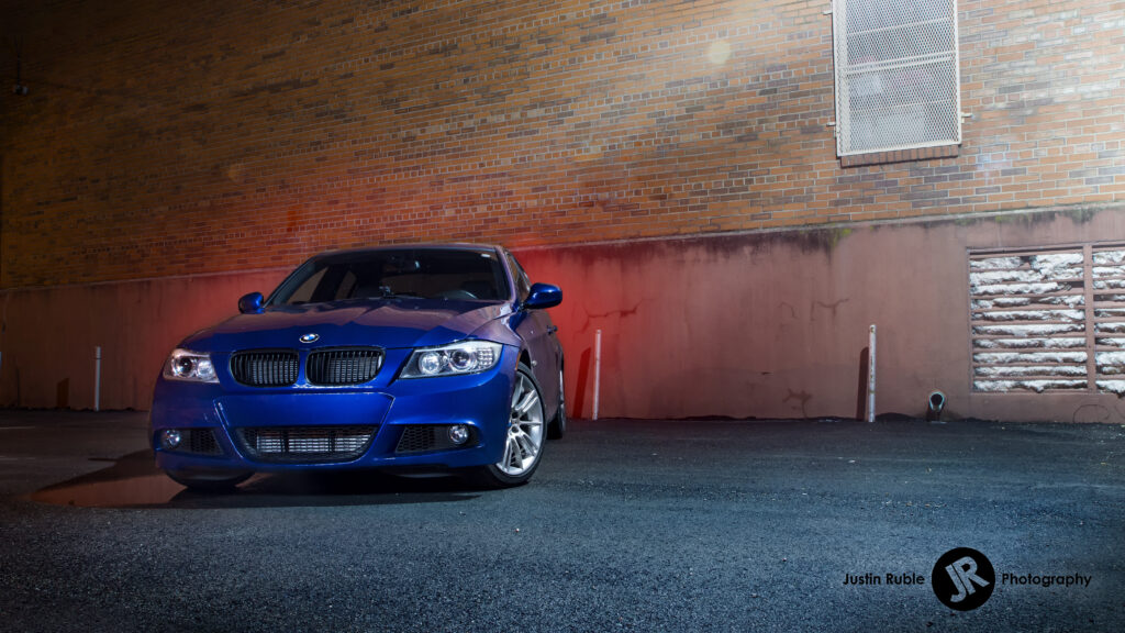 Striking Blue BMW Front View Wallpaper Against Urban Brick Background