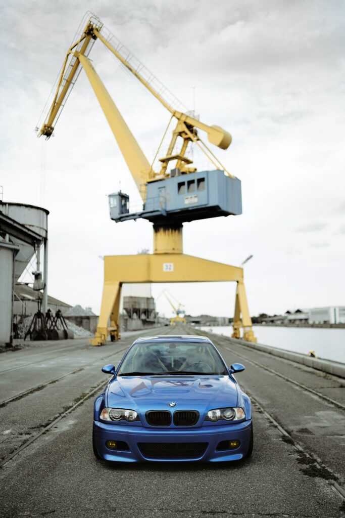 Front View Blue BMW Wallpaper on Industrial Road with Yellow Crane