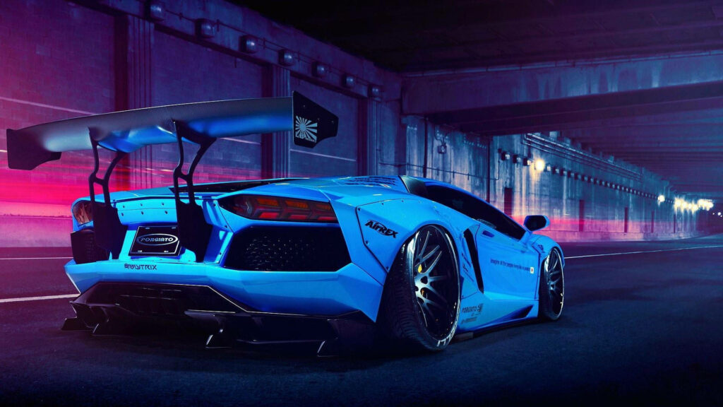 Striking blue sports car with large spoiler illuminated by purple and blue tunnel lights wallpaper