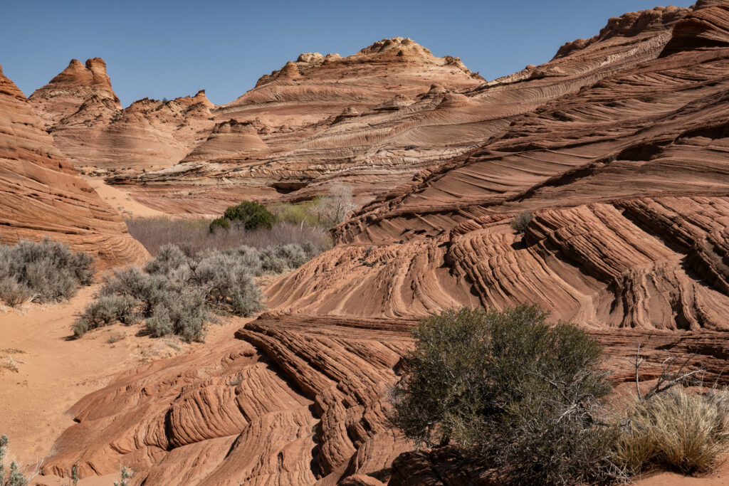 Striking desert landscape with rugged brown mountains and rock formations under clear blue sky Wallpaper