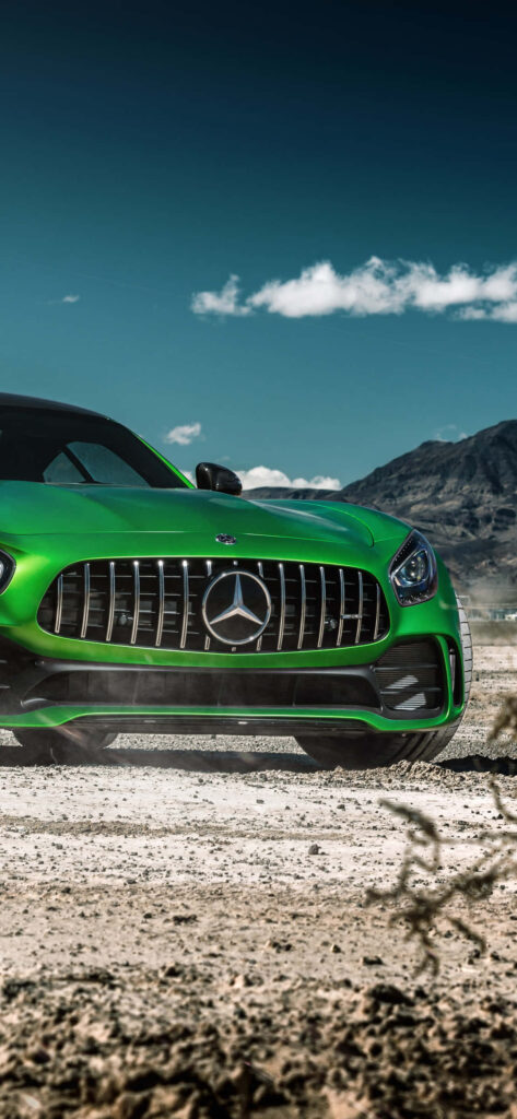 Green Mercedes AMG parked on rugged terrain with majestic mountains under clear blue sky wallpaper