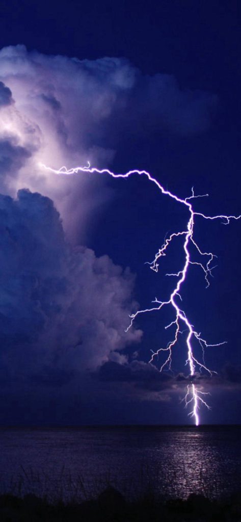 Striking lightning bolt illuminates deep indigo sky over dark ocean storm clouds iPhone wallpaper