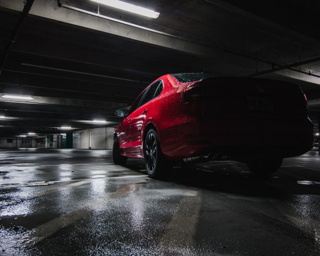 Red Car in Underground Garage: Reflections & Dramatic Background Wallpaper