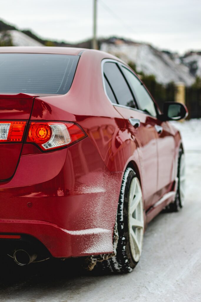Vibrant Red Car Amidst Snowy Winter Landscape: Striking Wallpaper