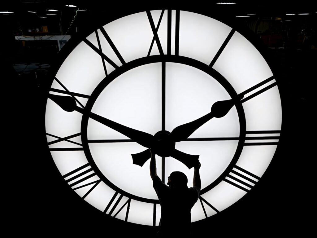 Silhouette of person adjusting giant illuminated clock hands symbolizing time and change wallpaper