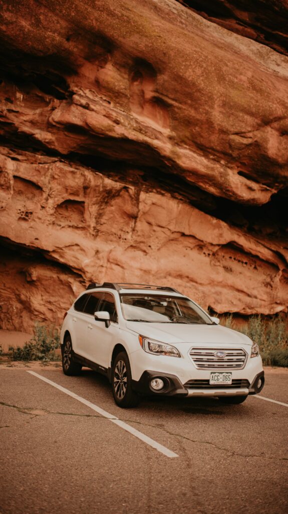 White Subaru Car Against Rugged Rocks - Striking Wallpaper Background